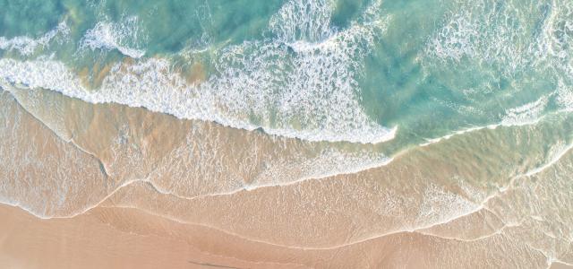 Soft blue ocean wave on clean sandy beach