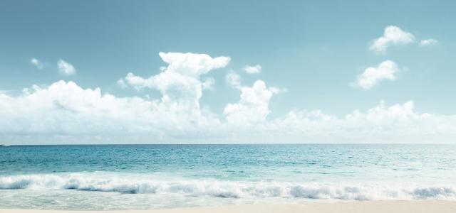 Soft blue ocean wave on clean sandy beach